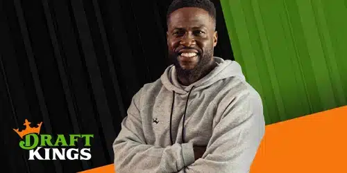 Kevin Hart smiling and wearing a gray hoodie with his arms crossed. The DraftKings logo is visible in the bottom left corner. The background features a split design with black stripes on the left and green stripes on the right, meeting an orange diagonal stripe at the bottom.